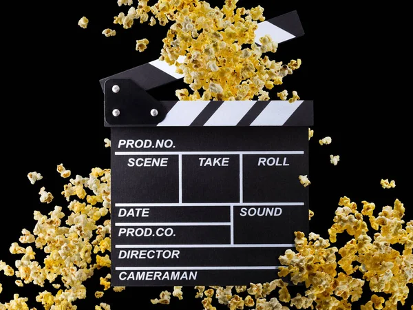 Flying popcorn and film clapper board isolated on black background
