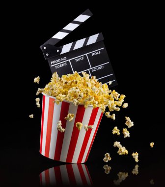 Uçan patlamış mısır ve film alkışları siyah zemin üzerinde izole edilmiş, televizyon veya sinema konsepti.
