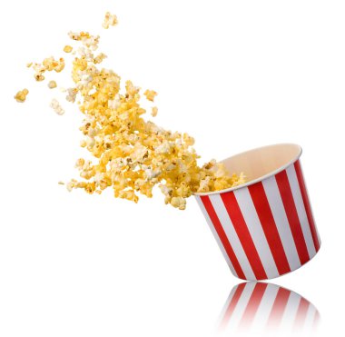 Beyaz arka planda izole edilmiş kağıt şeritli kovadan uçan patlamış mısır. Sinema kavramı ya da TV izlemek.