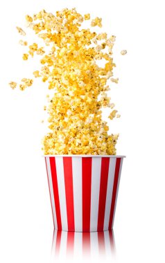Beyaz arka planda izole edilmiş kağıt şeritli kovadan uçan patlamış mısır. Sinema kavramı ya da TV izlemek.