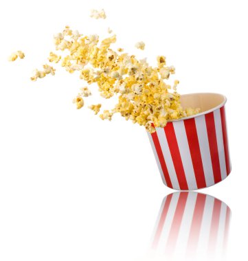 Beyaz arka planda izole edilmiş kağıt şeritli kovadan uçan patlamış mısır. Sinema kavramı ya da TV izlemek.