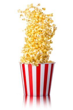 Beyaz arka planda izole edilmiş kağıt şeritli kovadan uçan patlamış mısır. Sinema kavramı ya da TV izlemek.
