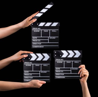 Bir set film alkış tahtası ve insan eli siyah arka planda izole edilmiş..