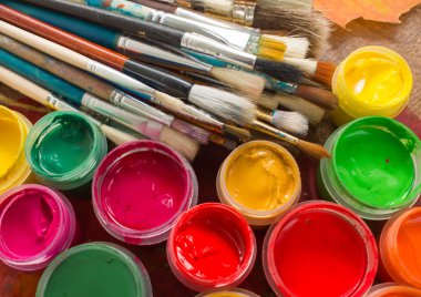 Boyalar, fırçalar, ahşap arka plan üzerinde sonbahar yaprakları.