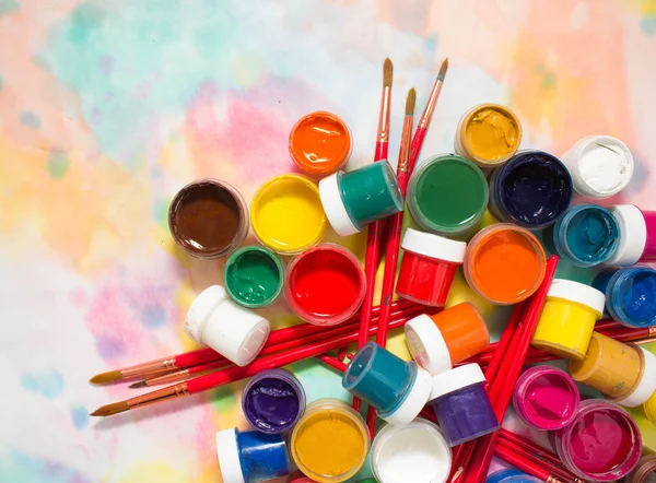 Paints, brushes and palette on the colorful background. Royalty Free Stock Images