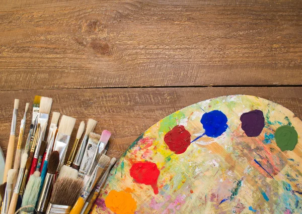 Tintas, pincéis e paleta sobre o fundo de madeira . — Fotografia de Stock