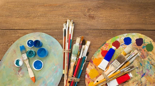 Pinturas, pinceles y paletas sobre el fondo de madera . — Foto de Stock