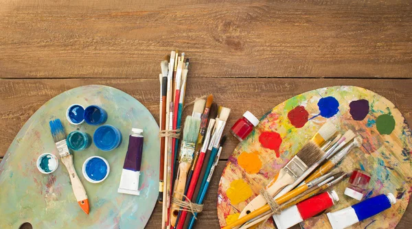 Färger, penslar och palett på trä bakgrund. — Stockfoto