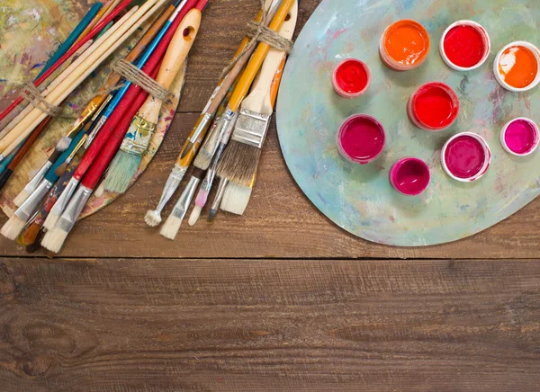 Tintas, pincéis e paleta sobre o fundo de madeira . — Fotografia de Stock