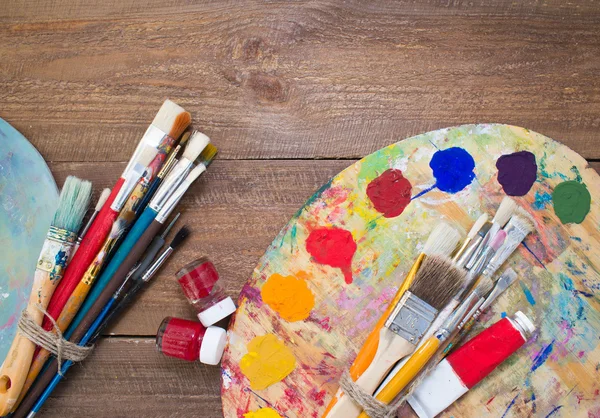 Paints, brushes and palette on the wood background. Royalty Free Stock Photos