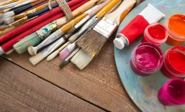 Renkli boyalar, fırçalar, palet ahşap arka plan üzerinde. 