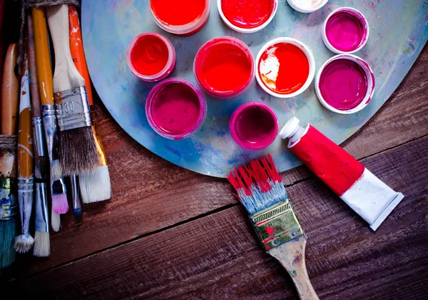 Renkli boyalar, fırçalar, palet ahşap arka plan üzerinde. 