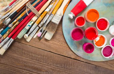 Renkli boyalar, fırçalar, palet ahşap arka plan üzerinde. 