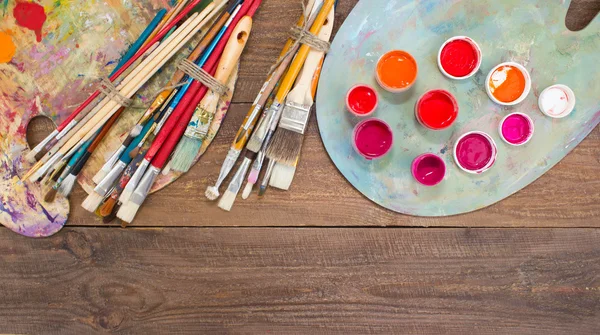 Pinturas coloridas, pinceles, paleta sobre el fondo de madera . — Foto de Stock