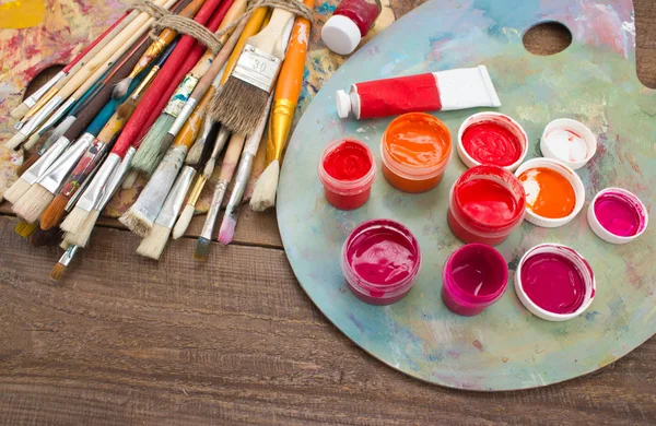 Tintas coloridas, pincéis, paleta sobre o fundo de madeira . — Fotografia de Stock