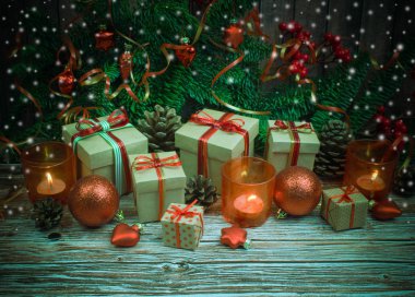 Noel ve yeni yıl arka plan: cam oyuncaklar, mumlar ve hediyeler ahşap arka plan üzerinde renkli