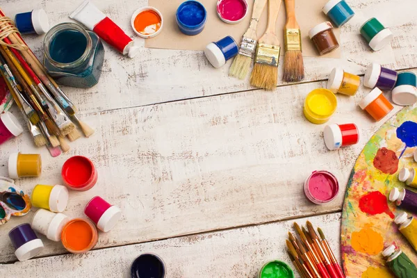 Paints, brushes and palette on the white wood background. — Stock Photo, Image