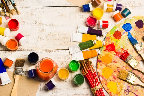 Tintas, pincéis e paleta sobre o fundo de madeira branca . — Fotografia de Stock