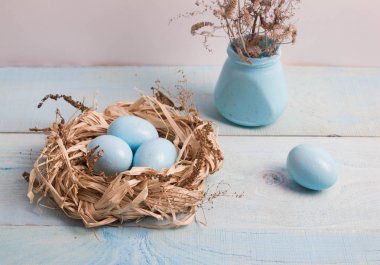 Mavi Paskalya yumurta yuvada ahşap arka plan üzerinde kuru ot ile vazo.