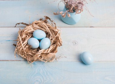 Mavi Paskalya yumurta yuvada ahşap arka plan üzerinde kuru ot ile vazo.