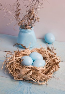 Mavi Paskalya yumurta yuvada ahşap arka plan üzerinde kuru ot ile vazo.