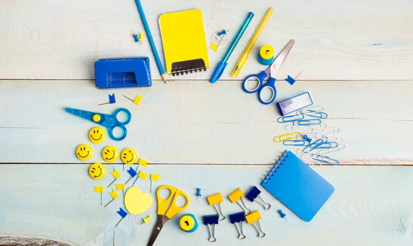 School stationery products such as paper clips, pins, notebooks, pens, pencils, rulers, scissors lying on wooden table with space to write your text