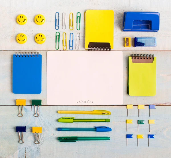 School stationery products such as paper clips, pins, notebooks, pens, pencils, rulers, scissors lying on wooden table with space to write your text