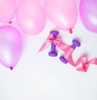 Beyaz arka planda pembe kurdeleli halterler ve balonlar