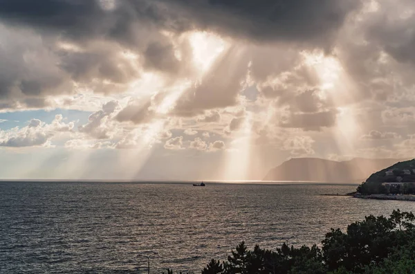 Güneşin ışınları Karadeniz kıyısındaki bulutların arasından geçiyor. Novorossiysk. Shirokaya Köyü Balka