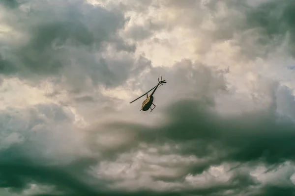 Büyük bir helikopter bulutlu yaz gökyüzünün altında gökyüzünde uçuyor.