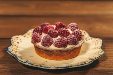 Lezzetli ahududulu mini tartlar koyu arkaplanda krem şantili turtalar.