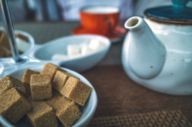 Kettle 'ın arka planındaki masada duran kahverengi kamış şekeri parçaları.