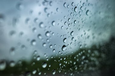Camdaki yağmur damlaları, gri arka planda. Doğal ışık