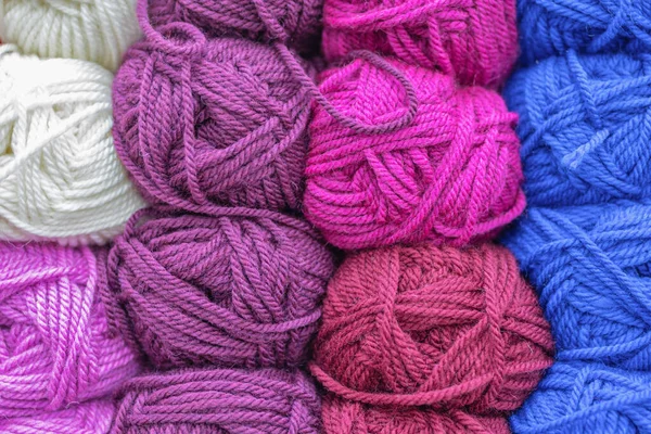 Multicolored wool balls of yarn. Background of colored yarn balls. Embroidery. Knitting. Hobbies and leisure.