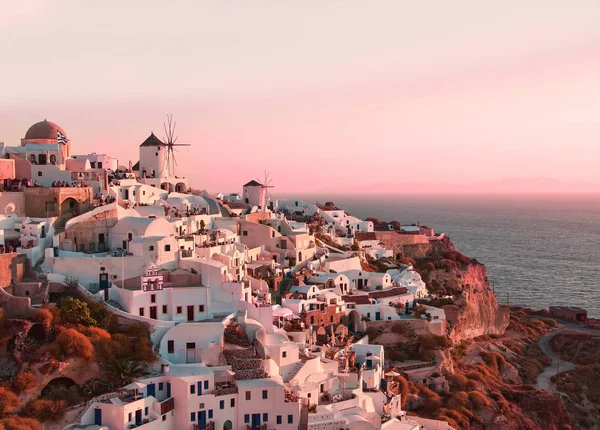 Hermoso paisaje clásico con edificios blancos y molinos de viento antiguos en Oia en la isla de Santorini, Grecia al atardecer —  Fotos de Stock
