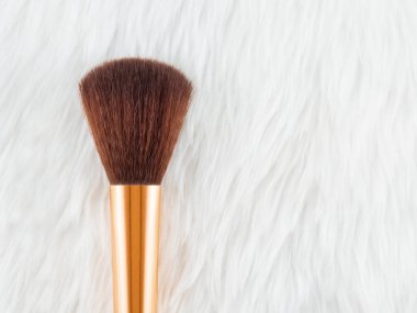 Yumuşak kürk masa örtüsüne yüz pudrası sürmek için makyaj fırçası. kırpma yolu ile.