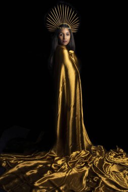 Güney Asyalı kadın altın kumaşa sarılmış ve altın bir başlık takıyor.