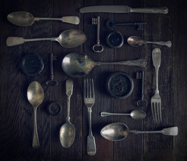 Kaliteli çatal bıçak, anahtarlar ve ağırlıklar kaba ahşap bir yüzeye yerleştirilmiş.