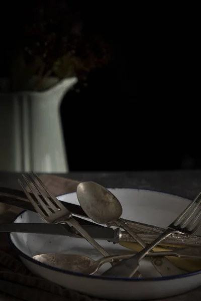 Vintage cutlery on a tin plate with a vintage jug in the background