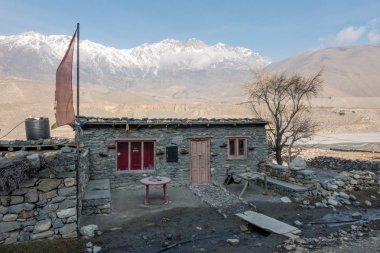 Taş ev, dua bayrakları ve kar pik