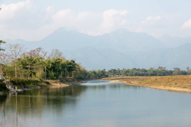 Nepal 'de ağaçlarla ve yüksek dağlarla kaplı sakin bir nehir..