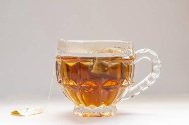 Beyaz arka planda taze demlenmiş cam bir fincan siyah çay..