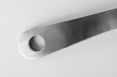 Beyaz arka planda gümüş renkli bir kaşık sapı.