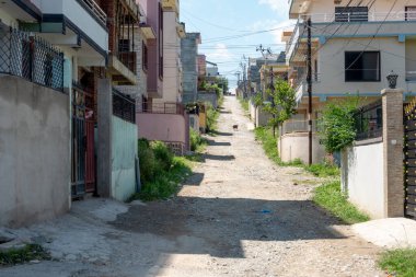 Avlularla çevrili dar toprak bir yol. Toplumdan izolasyon yaratmak.