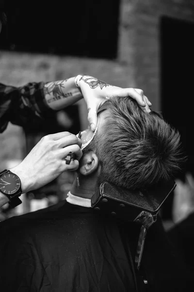 Jovem barbeiro fazendo corte de cabelo na barbearia — Fotografia de Stock