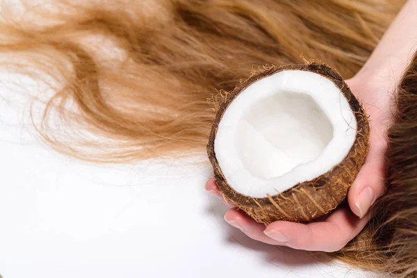 Weibchen halten Kokosnuss in der Hand bei der Behandlung von Haarschäden, Haarschäden, Gesundheits- und Schönheitskonzept. — Stockfoto