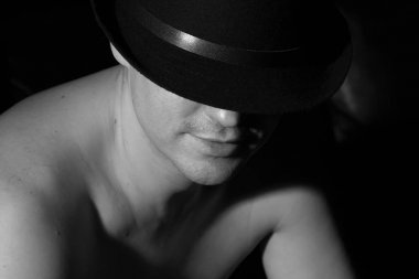 Çıplak omuz ile siyah şapkalı bir adam. Siyah ve beyaz.