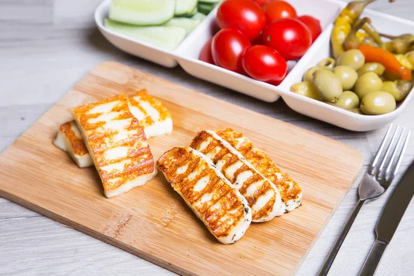 Haloumi peynir zeytin, kiraz, salatalık ve biber ile ahşap bir tahta üzerinde ızgara. 