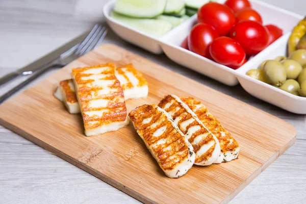 Haloumi peynir zeytin, kiraz, salatalık ve biber ile ahşap bir tahta üzerinde ızgara. 