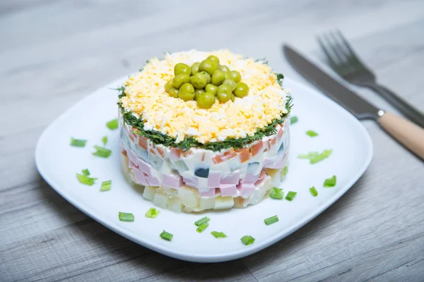 Salade traditionnelle russe olivier sur une assiette blanche — Photo